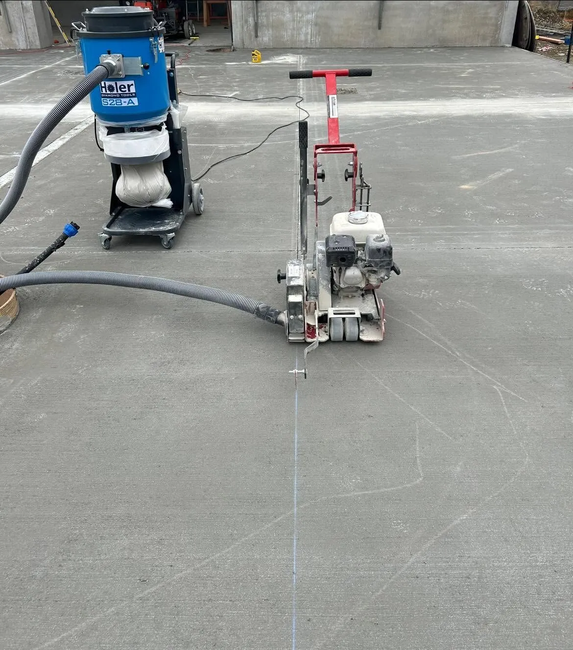 Dust extraction vacuum hosed straight to the blade guard of a soft cut saw on a concrete floor in South Canterbury